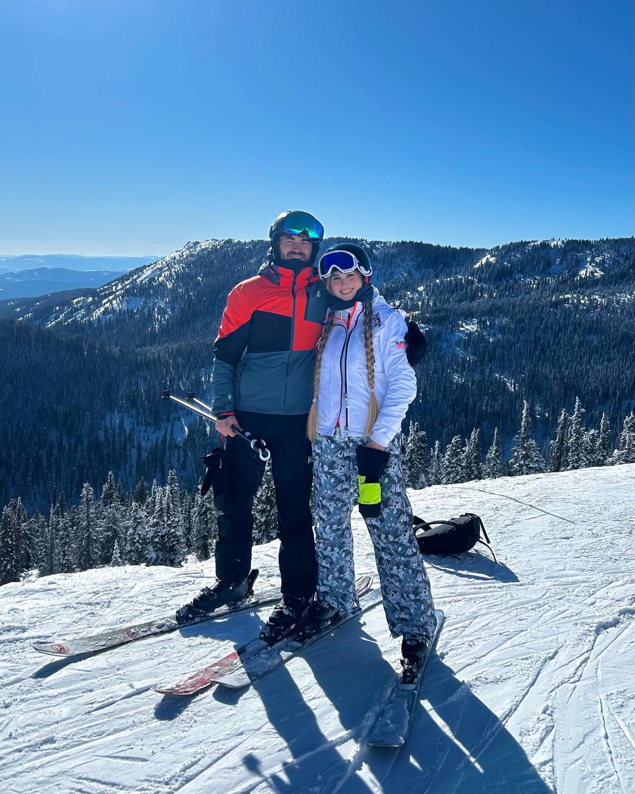 Callum and Celina on skis at the top of a mountain